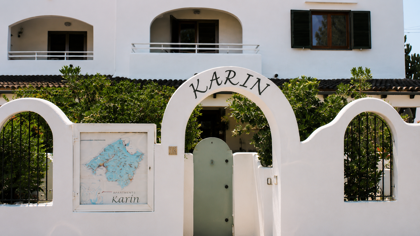 Original 'KARIN' wordmark hand-painted on the arched entryway of the whitewashed building