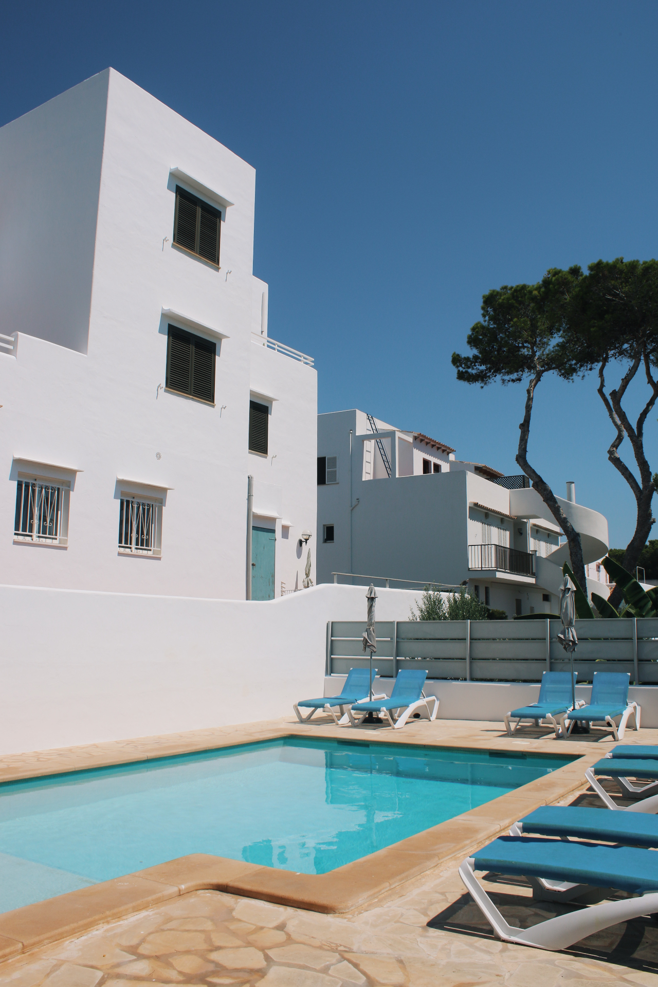 Residents-only pool at Karin Apartments with whitewashed façade and pine trees